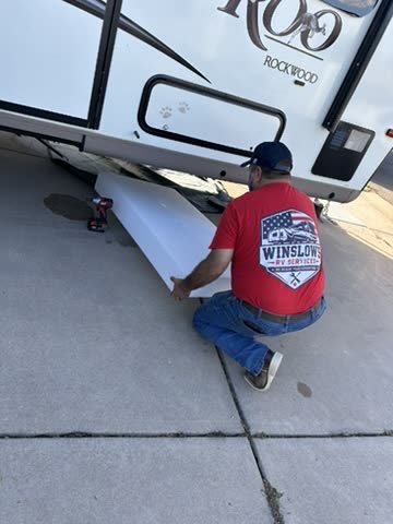 Technician kneeling at a Rockwood Roo lifting an underbelly panel