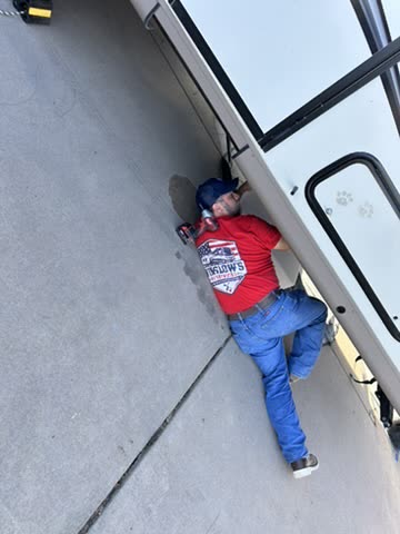 Technician lying along a trailer working on the frame