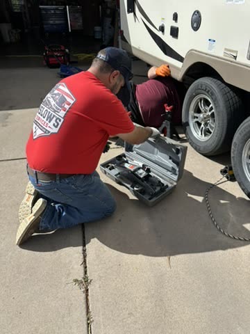 Technician opening a jack case next to a travel trailer wheel