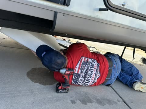 Technician drilling under a trailer next to an underbelly panel