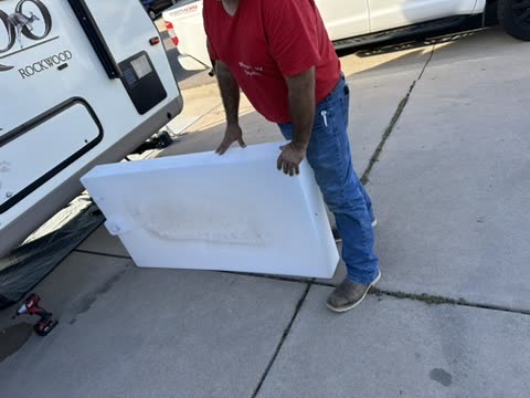 Ken carrying a removed freshwater tank beside a Rockwood trailer