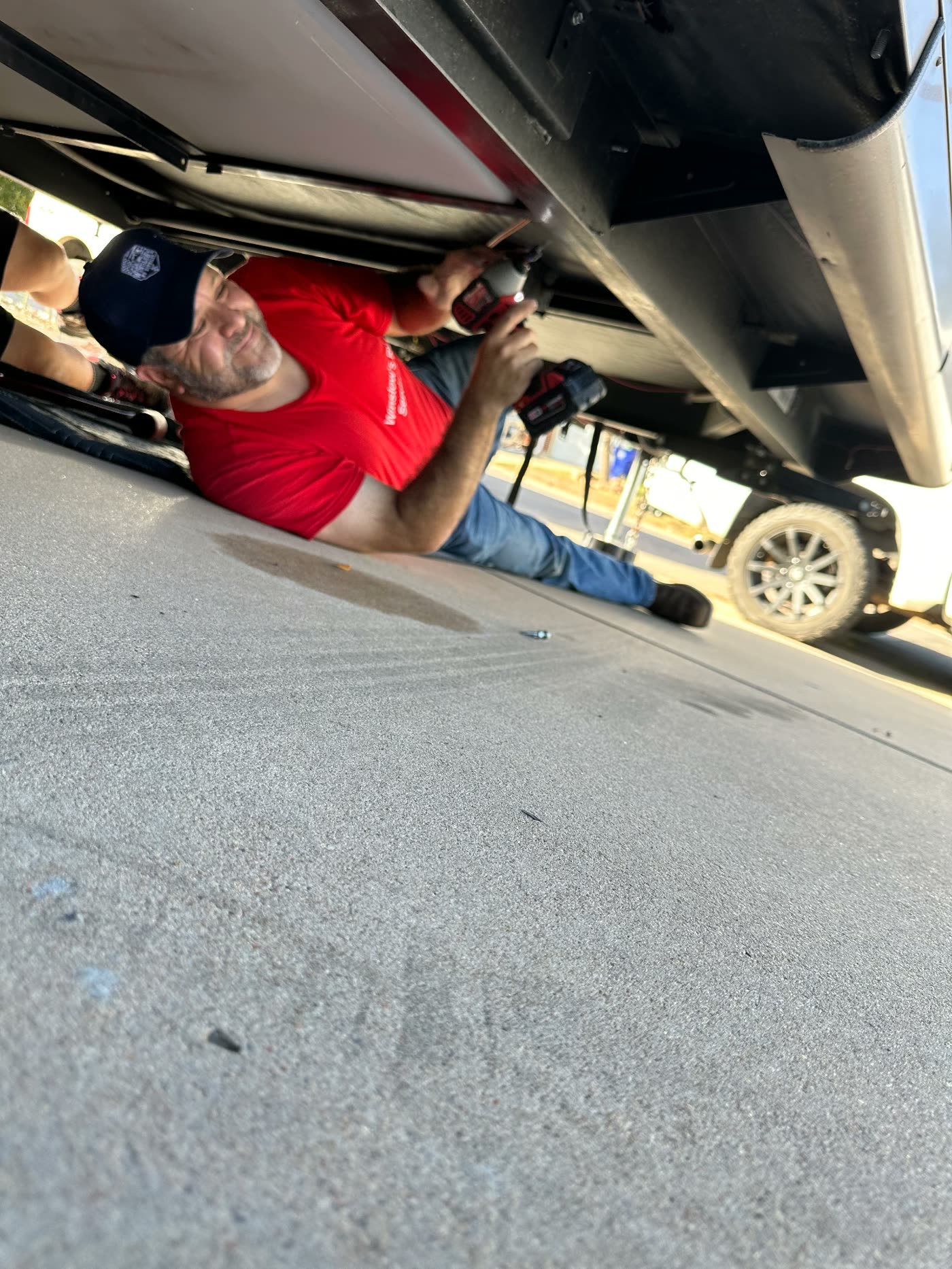 Ken Winslow smiling while driving fasteners under an RV