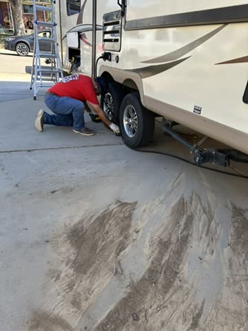 Technician kneeling to check a travel trailer tire