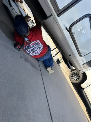 Technician working beneath an RV with a drill